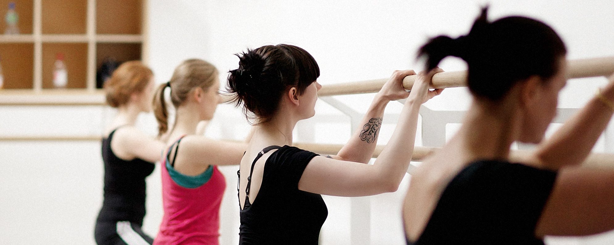 Dancers at the barre in a full plie position.
