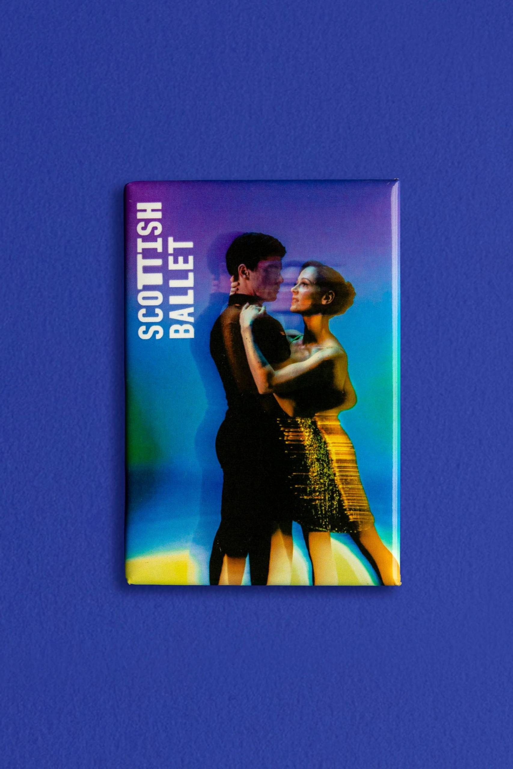 A rectangular magnet on a blue background shows two dancers embracing, with SCOTTISH BALLET written vertically in white text. The image has a colourful, iridescent effect.
